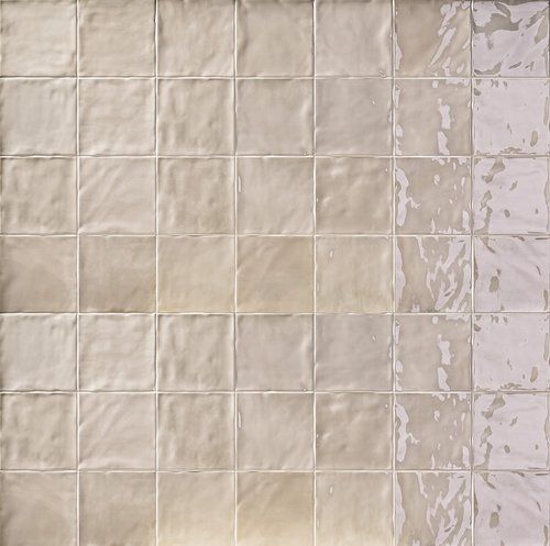 Beige square ceramic tiles with a textured, glossy finish, arranged in a grid.