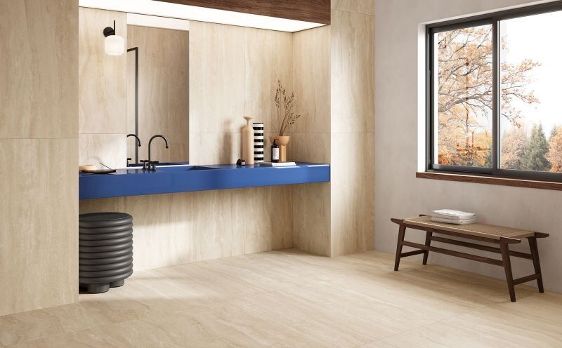 Bathroom with wood-like beige walls, a blue vanity, and a window overlooking autumn trees.