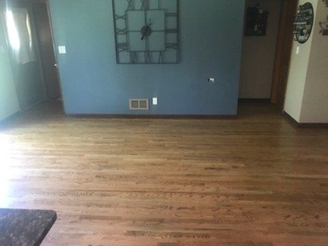 Hardwood floor with blue wall and large clock; doorway on left, another on right.