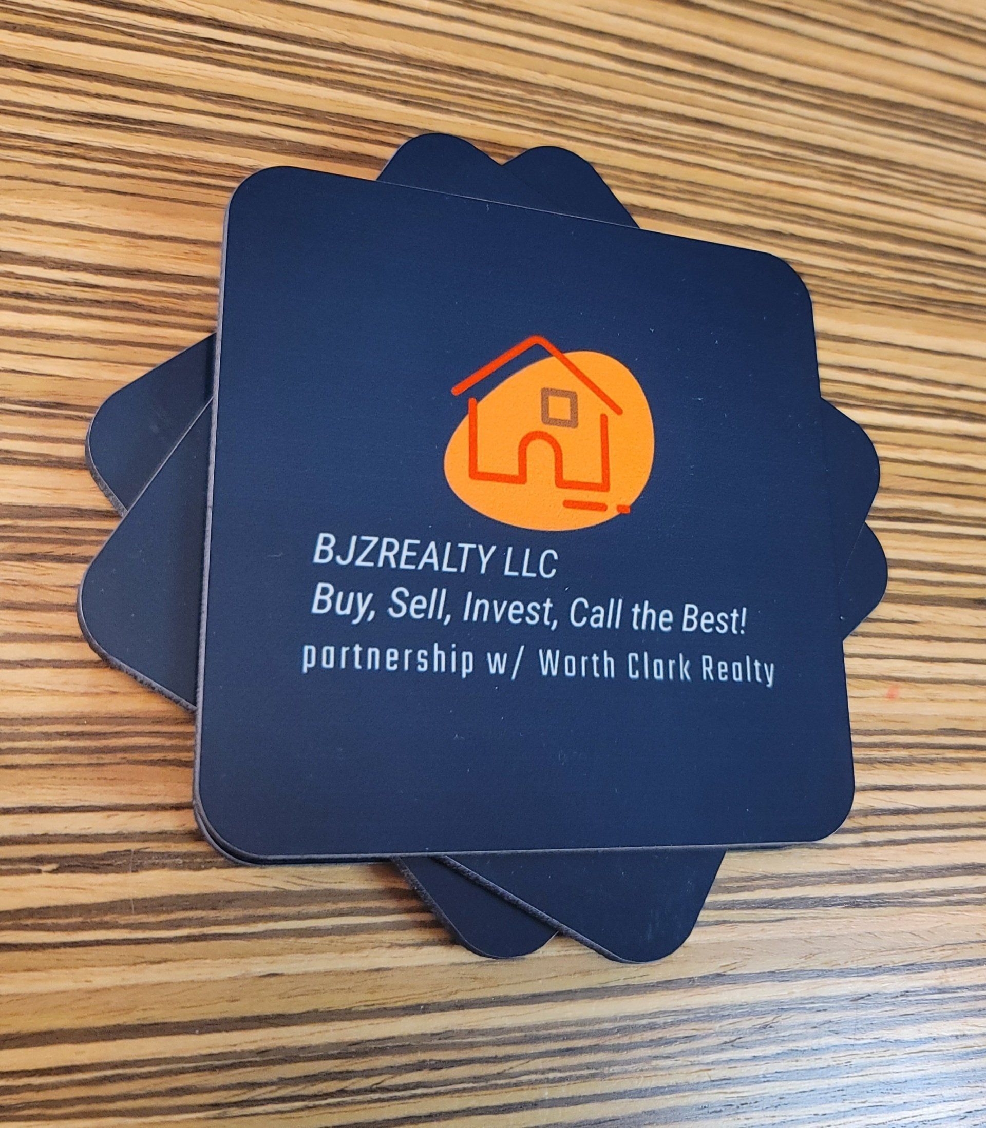 A business card for bjzrealty llc sits on a wooden table