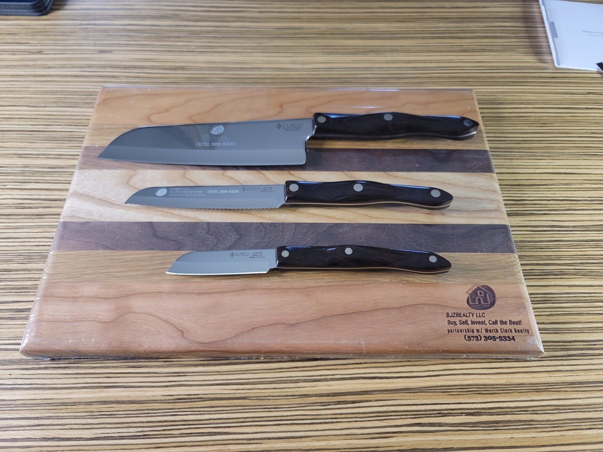 Three knives are sitting on a wooden cutting board.