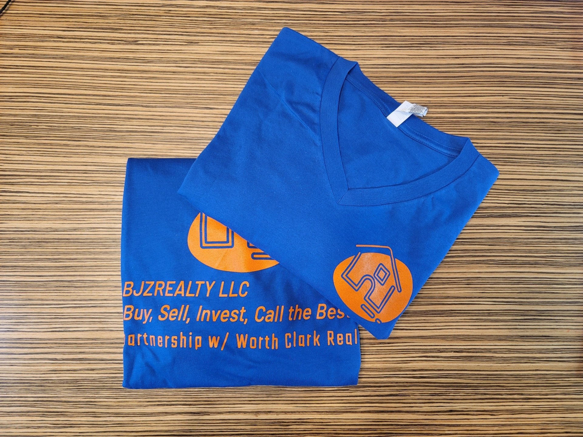 A blue t-shirt that says bjzrealty llc on it