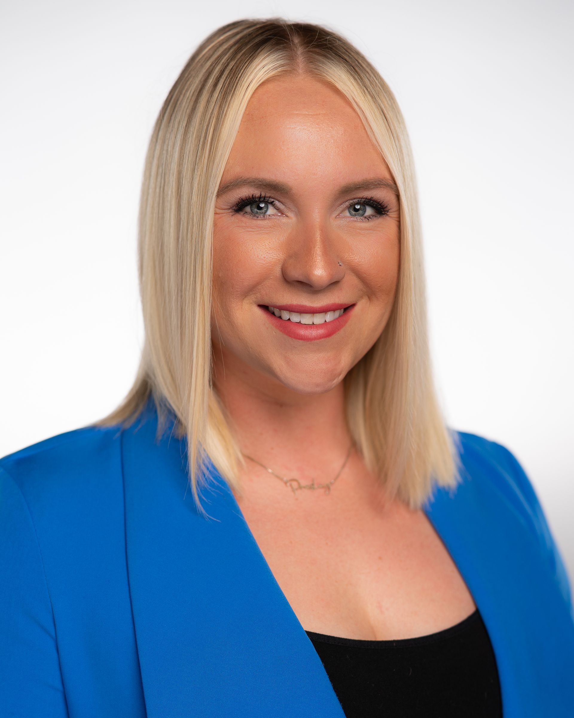 A woman is wearing a blue jacket and smiling for the camera.