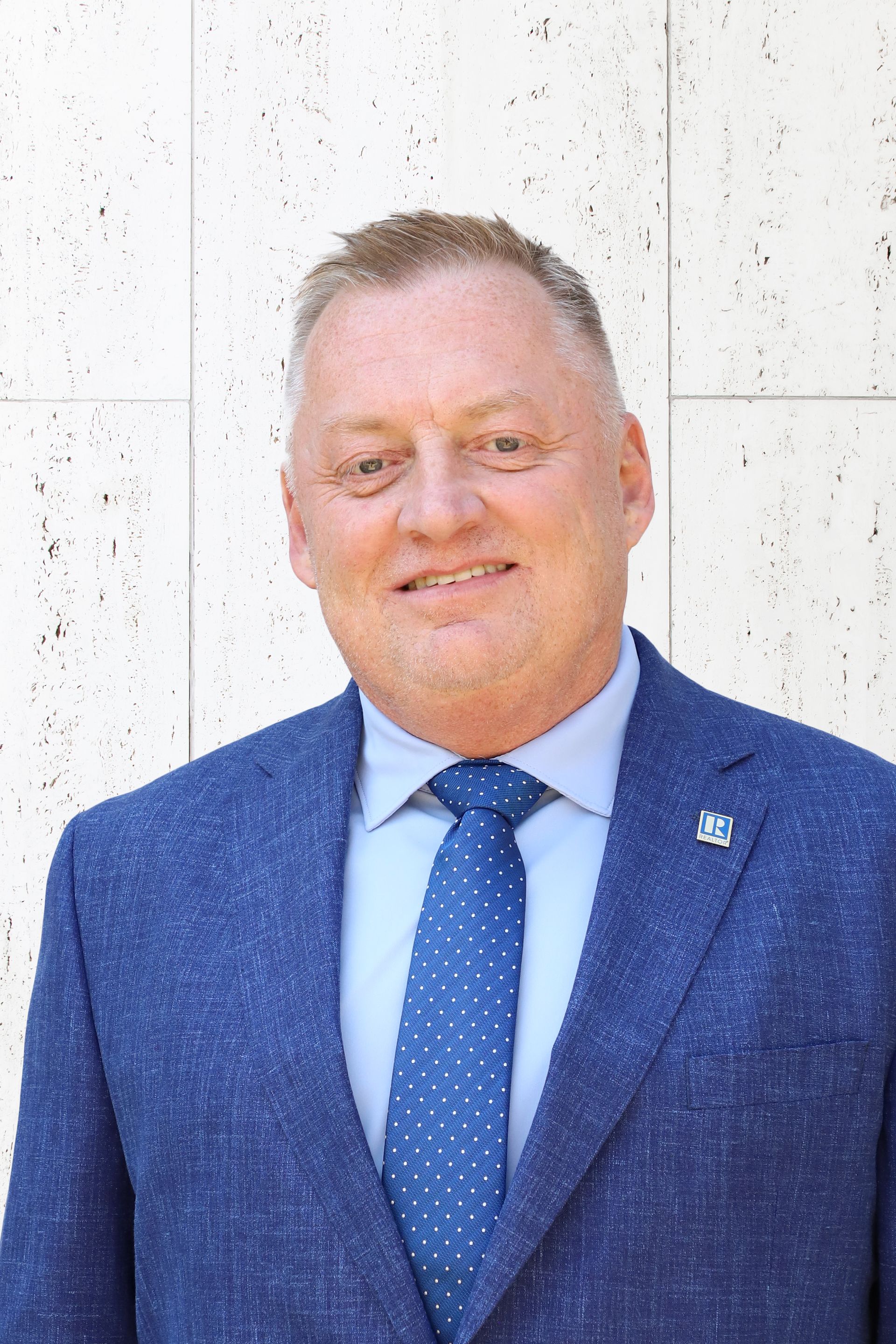 A man in a suit and tie is smiling for the camera.