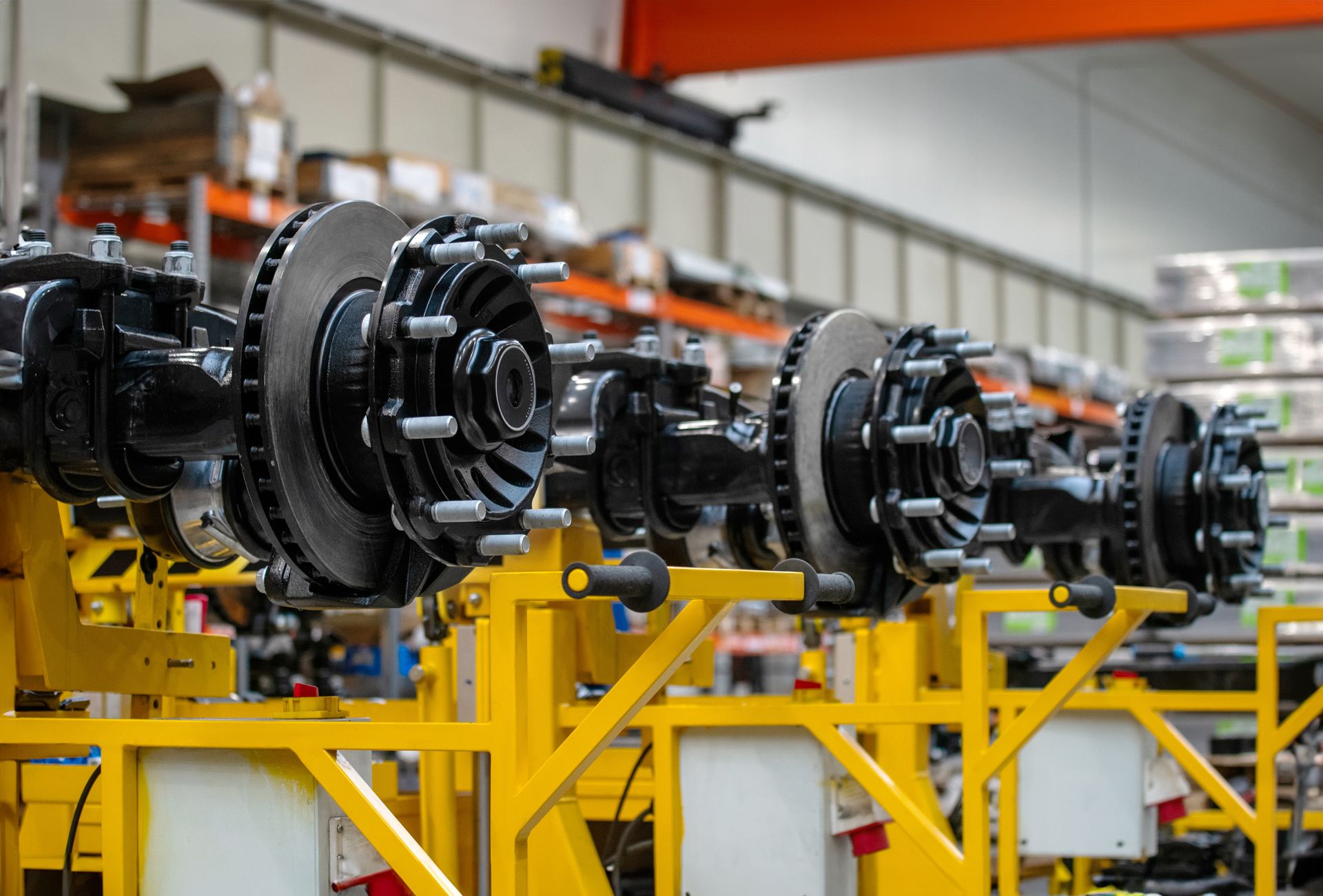 Row of black industrial machine assemblies on yellow factory stands in a production line