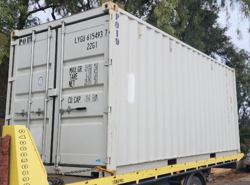 A White Shipping Container is Sitting on Top of a Yellow Tow Truck — Toowoomba Container Hire & Sales in Warwick, QLD