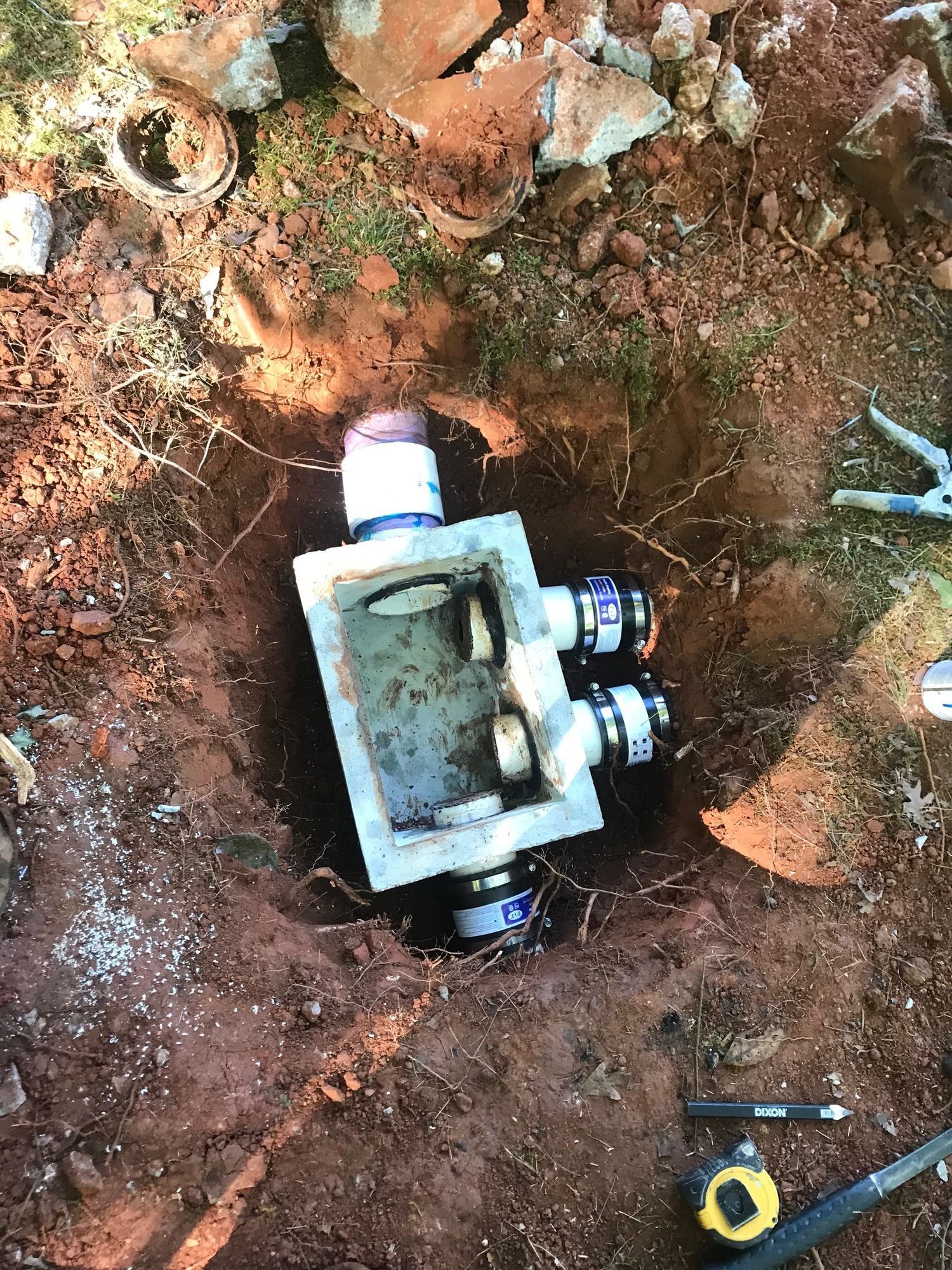A box is sitting in the dirt next to a tape measure.