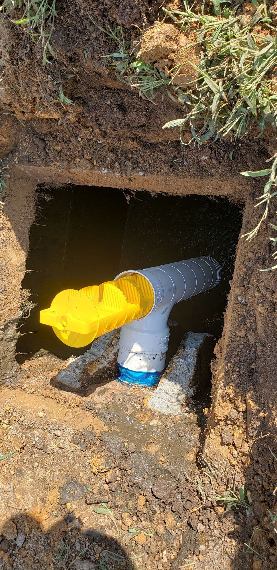 A yellow pipe is coming out of a hole in the ground.