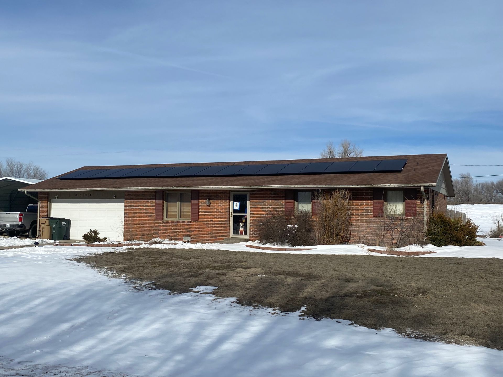 A house with solar panels on the roof is surrounded by snow.