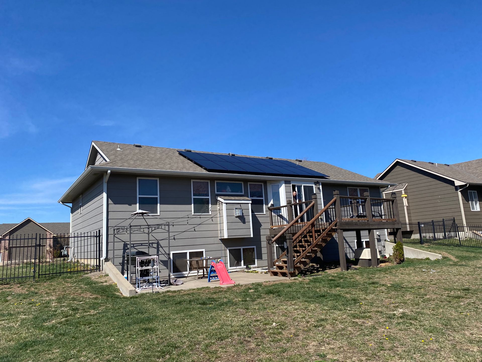 The back of a house with a deck and solar panels on the roof.