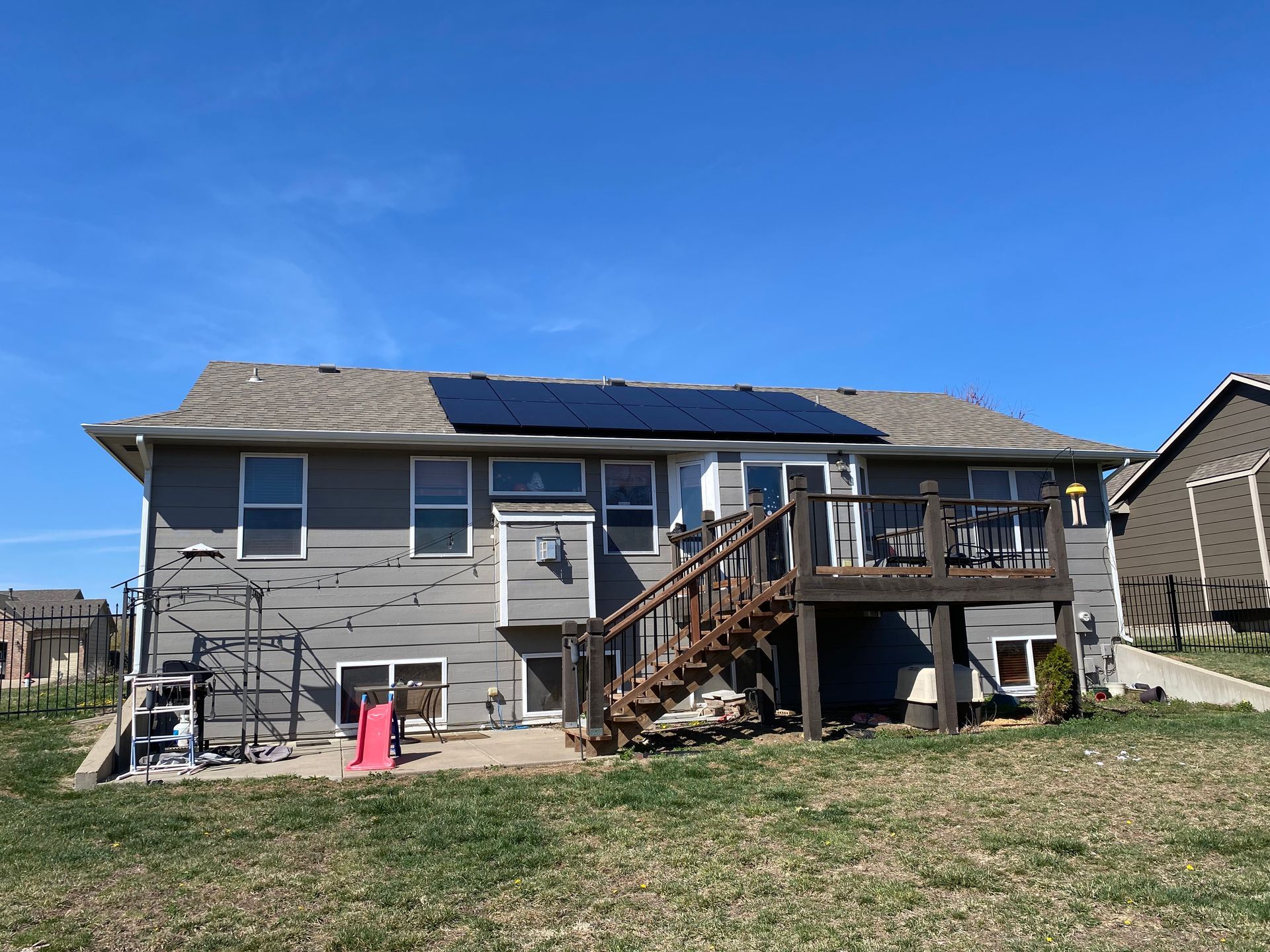 The back of a house with a deck and solar panels on the roof.