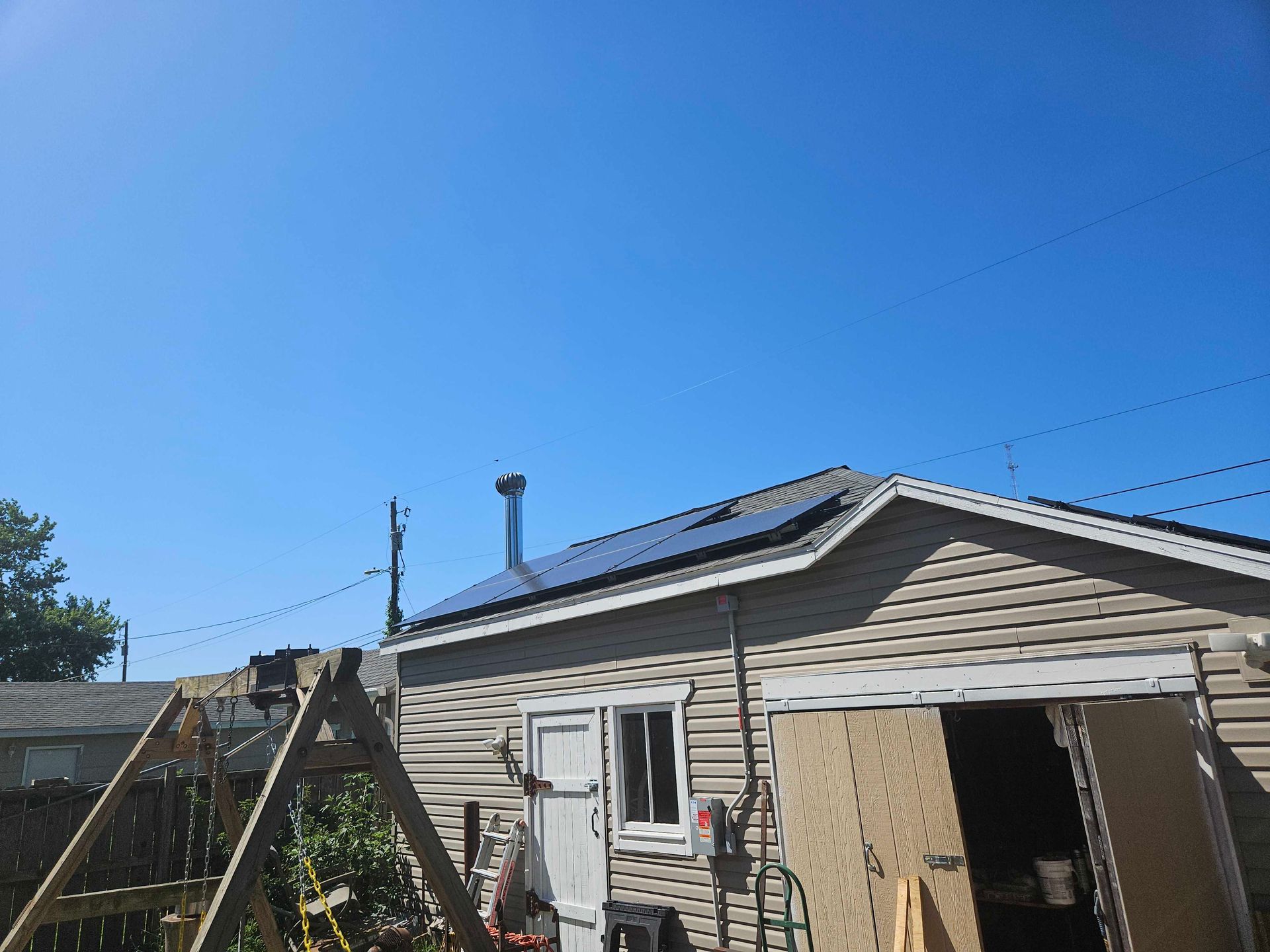 A house with solar panels on the roof and a blue sky in the background.