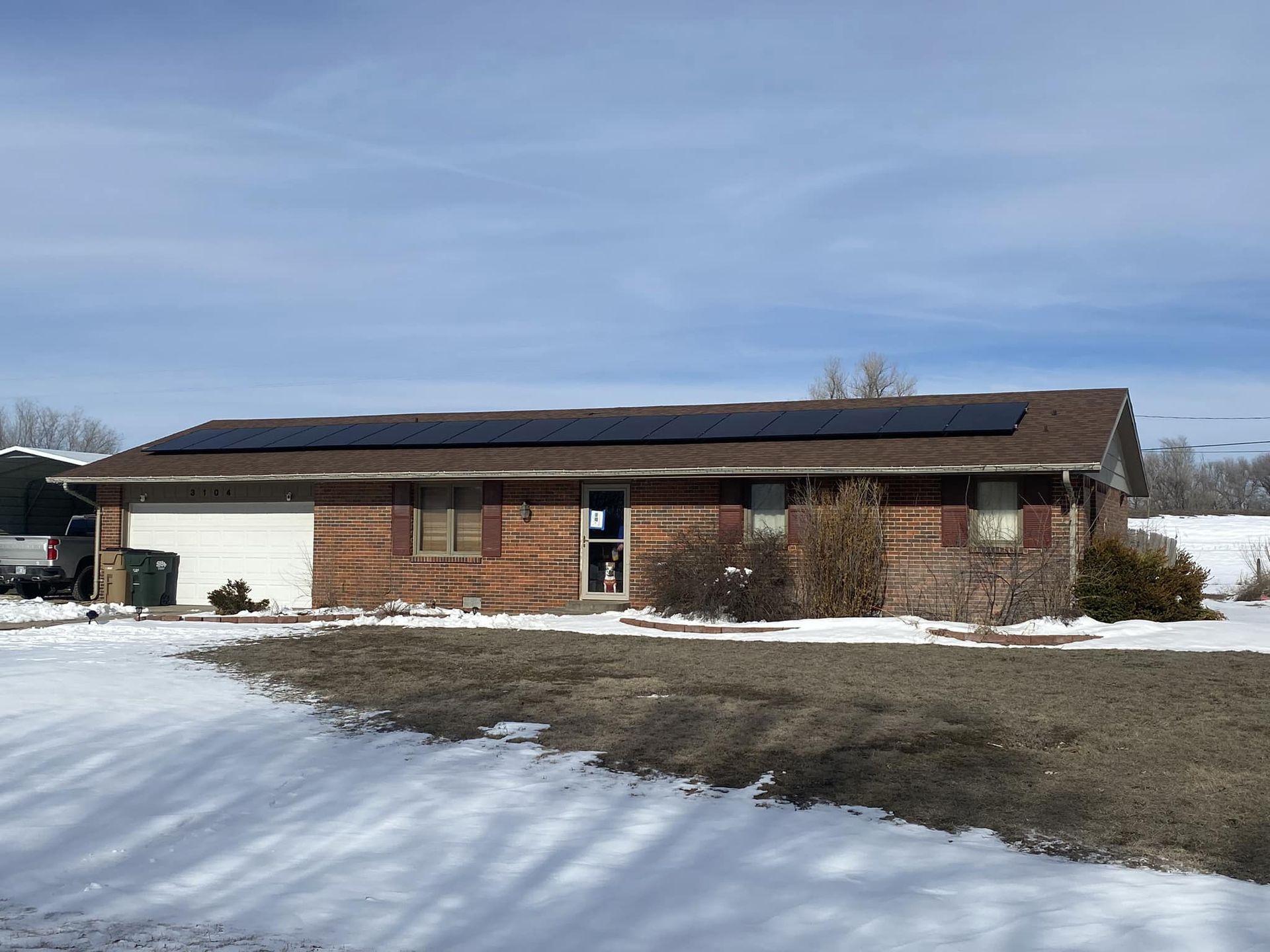 A house with solar panels on the roof is surrounded by snow.