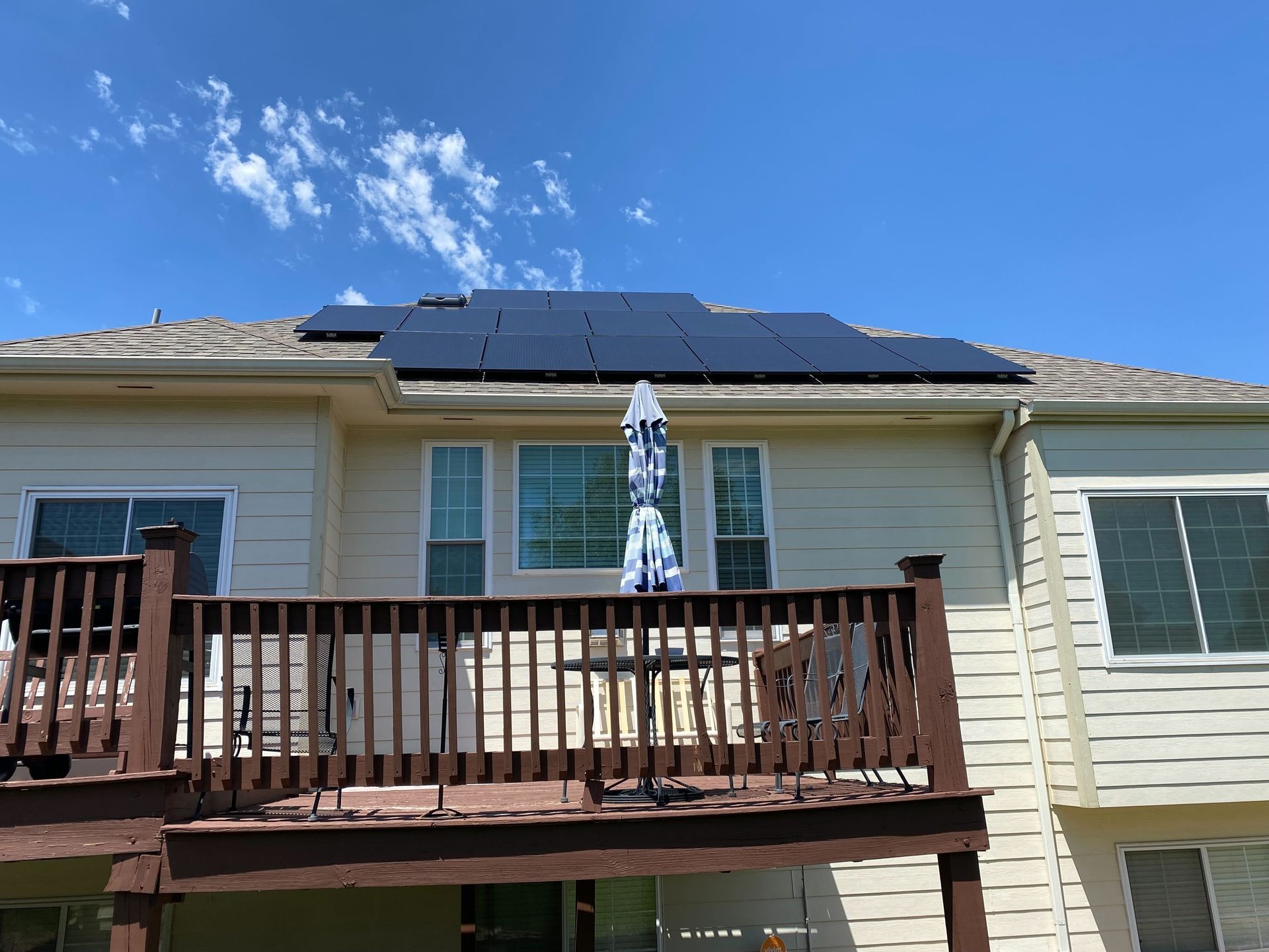 A house with a deck and solar panels on the roof.