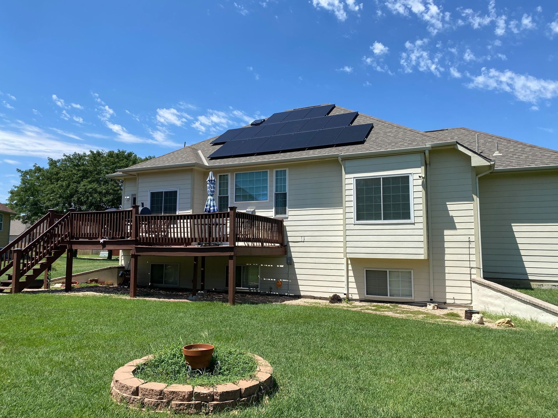 The back of a house with a deck and solar panels on the roof.