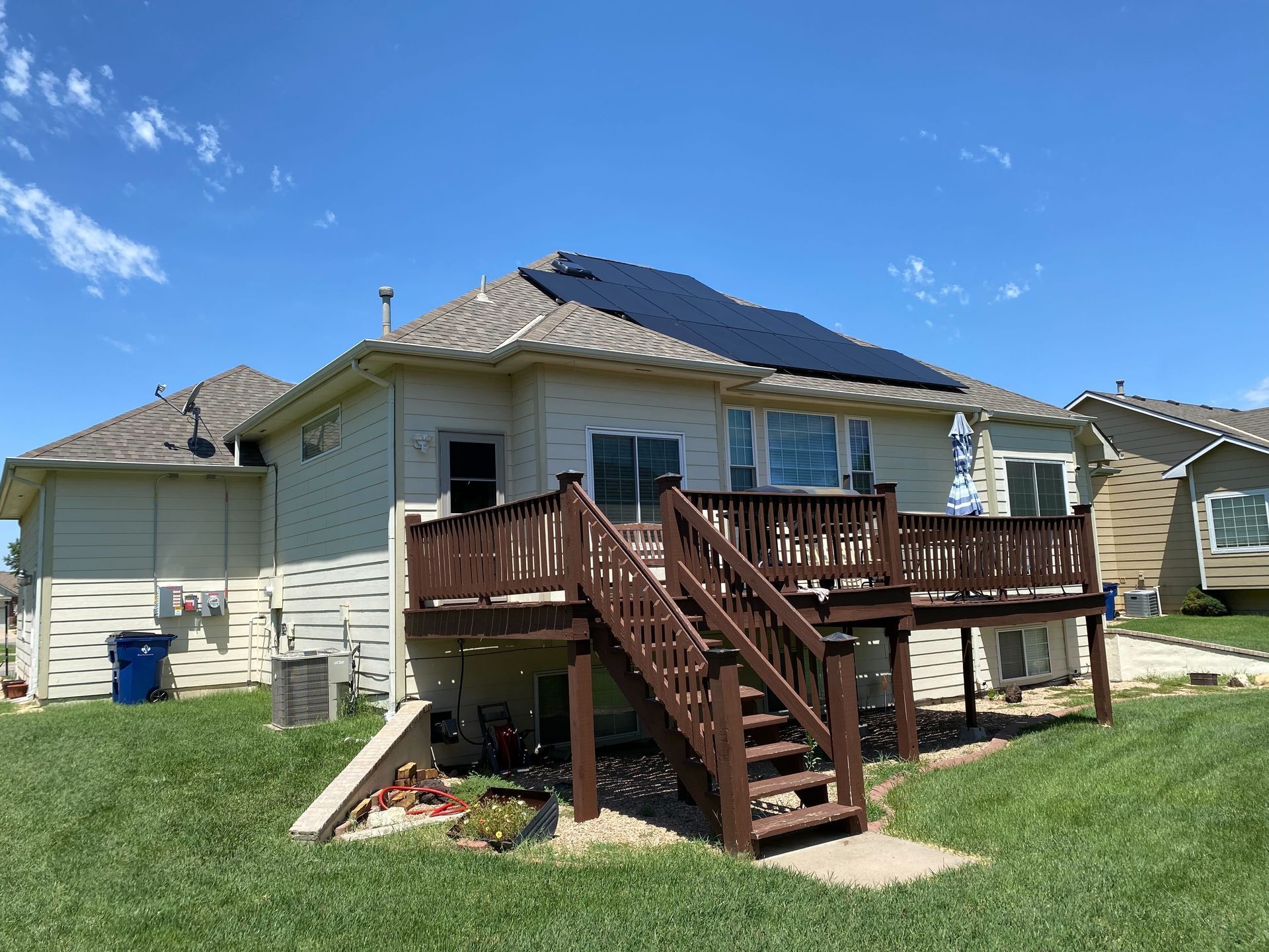 The back of a house with a deck and solar panels on the roof.