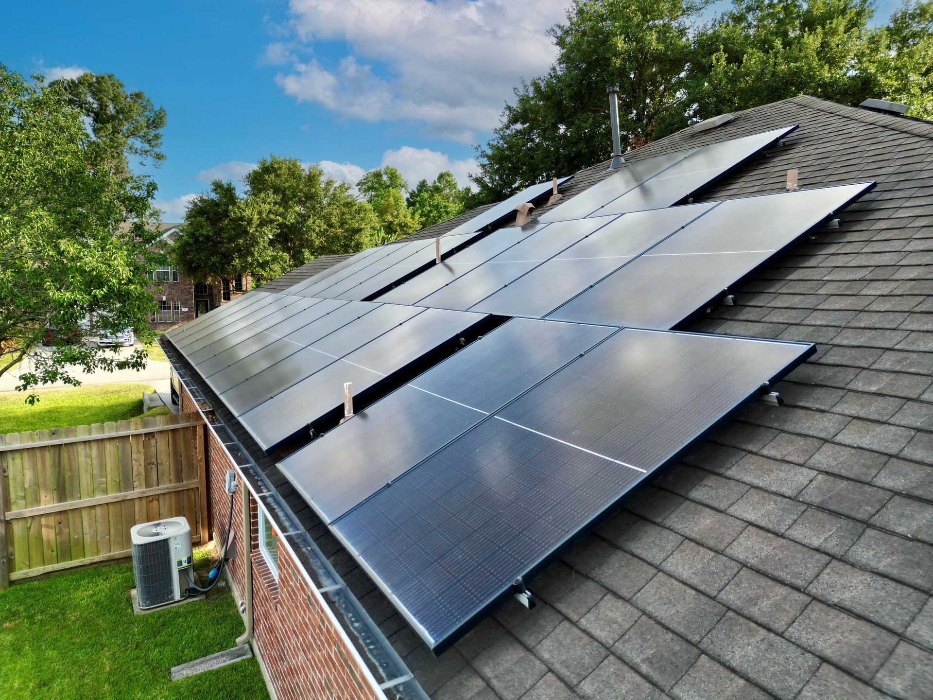 There are many solar panels on the roof of a house.