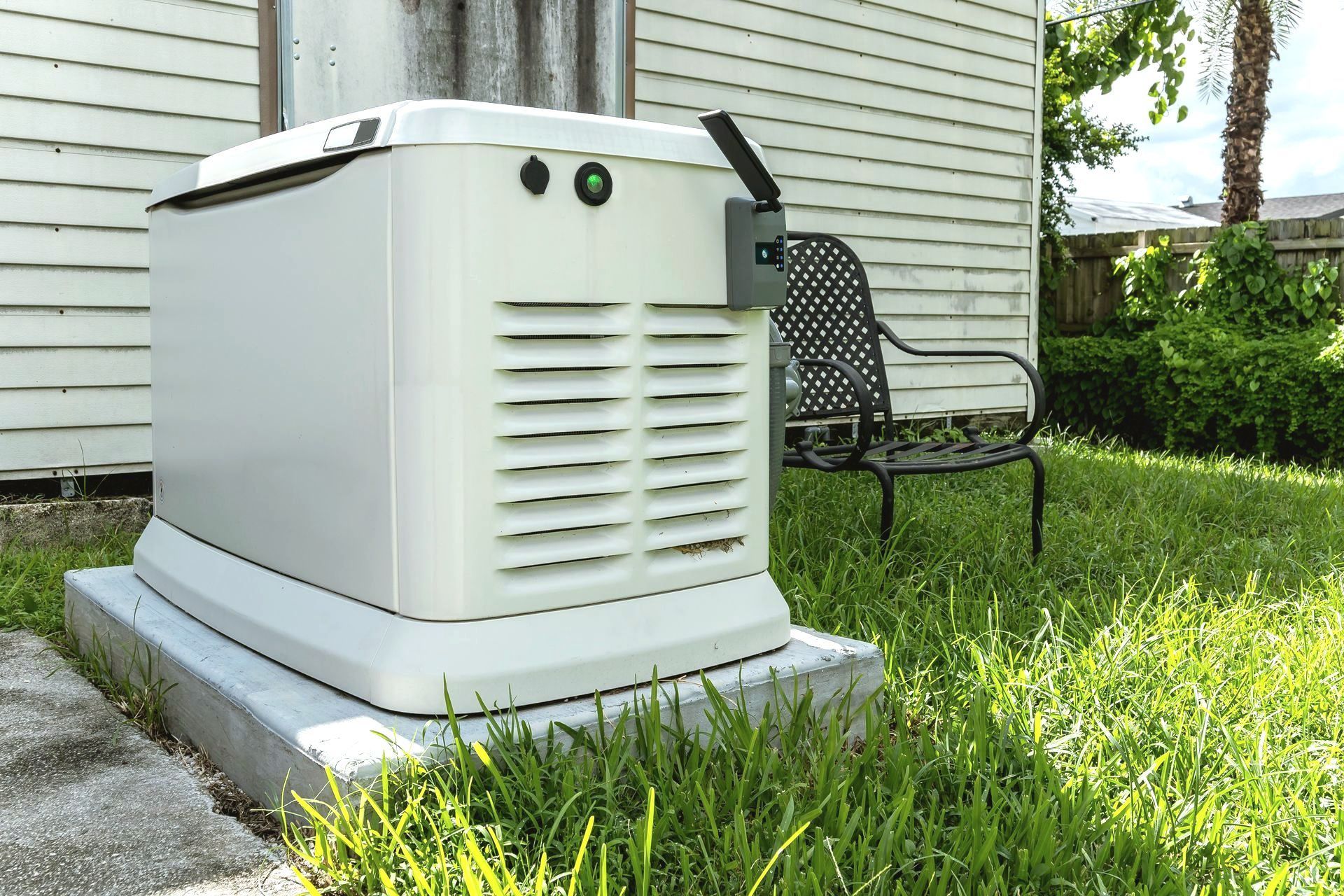 A generator is sitting in the grass in front of a house.