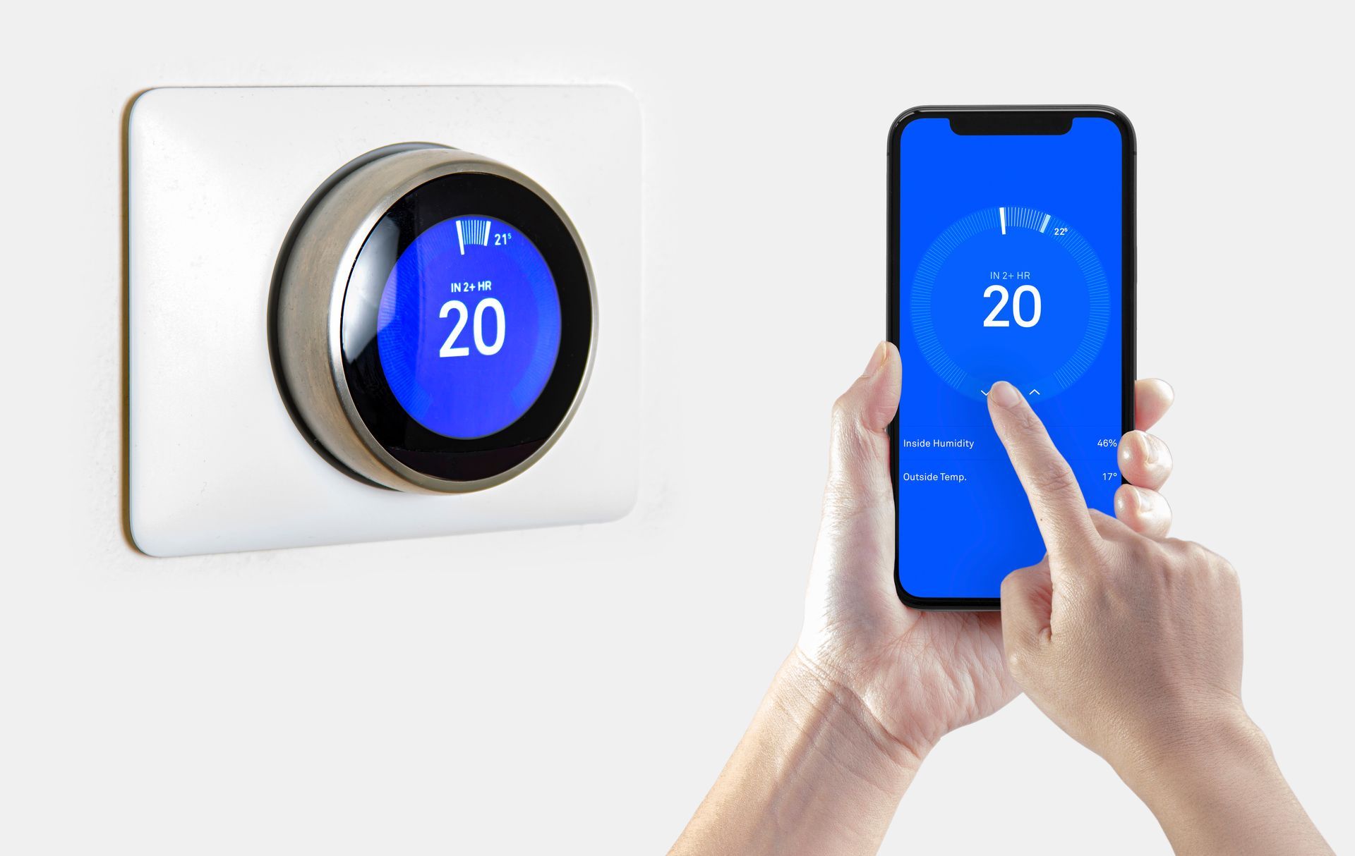 A person is using a smart phone to control a thermostat.