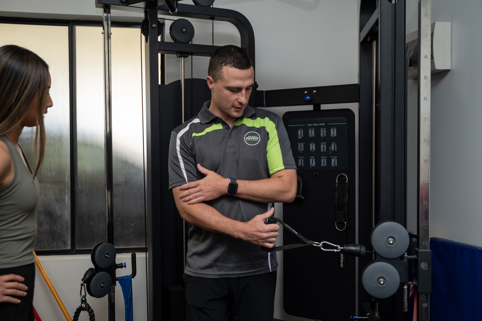 Male physio teaching a female client a shoulder rehab exercise