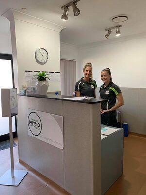 Two physiotherapists standing at reception smilin