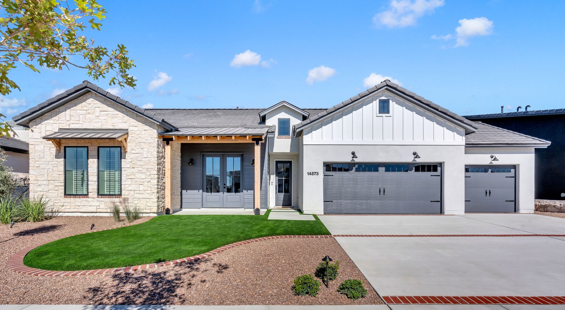 Modern single-story home with a brick exterior, grey accents, and a manicured lawn.