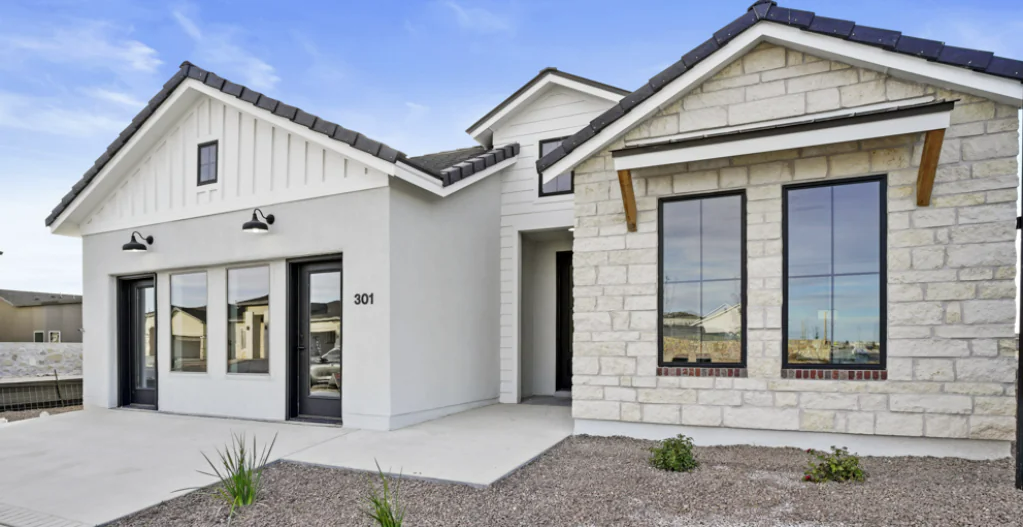 Modern home with stone and white siding, black-framed windows, and a gray driveway.