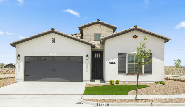 Light stucco house with gray garage door and black front door under a blue sky.