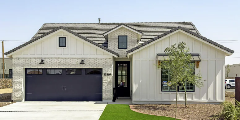 White farmhouse with a gray roof and dark blue garage door.