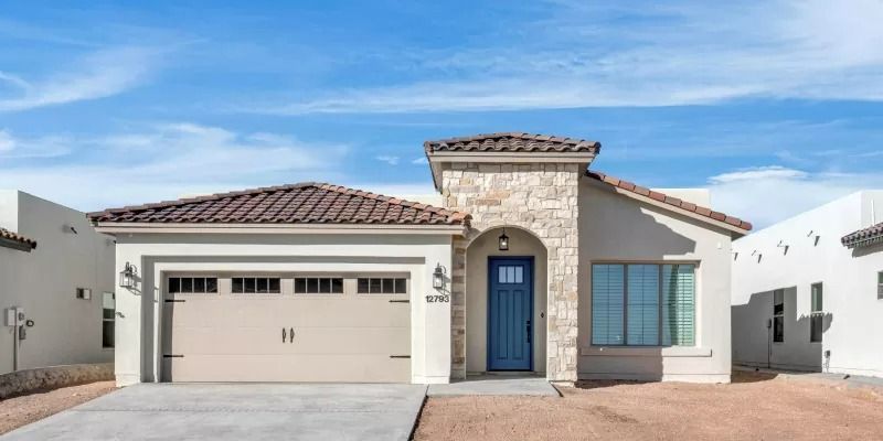 Exterior of a stucco house with a tiled roof, blue door, and tan garage door against a blue sky.