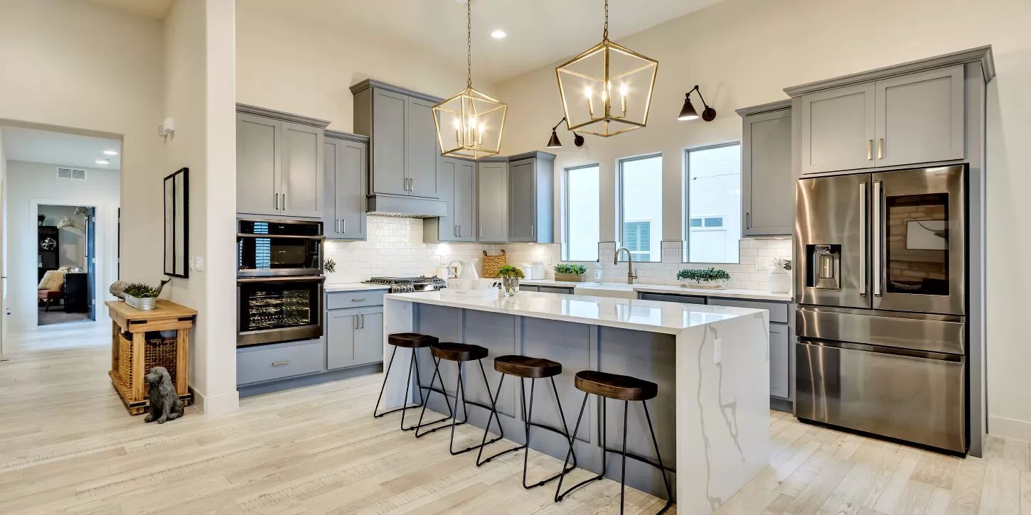 Modern kitchen with gray cabinets, white countertops, and a large island with stools.