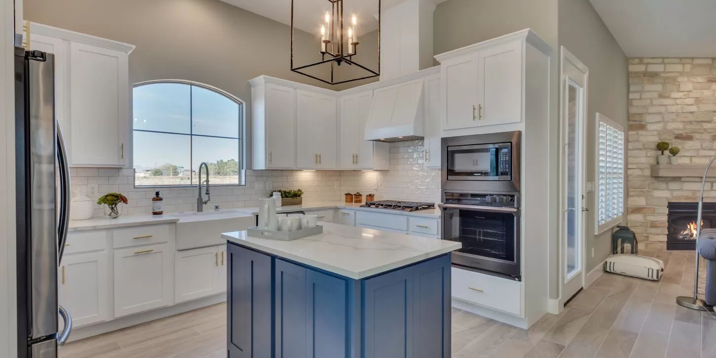 Modern kitchen with white cabinets, blue island, and a brick fireplace.