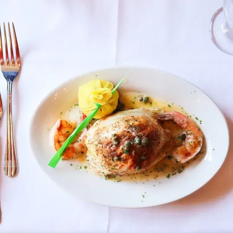 Fish entree with shrimp, lemon butter sauce, capers, and mashed potato on white plate.