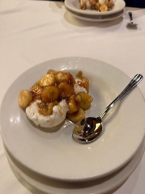 Banana foster dessert on a white plate with a spoon.