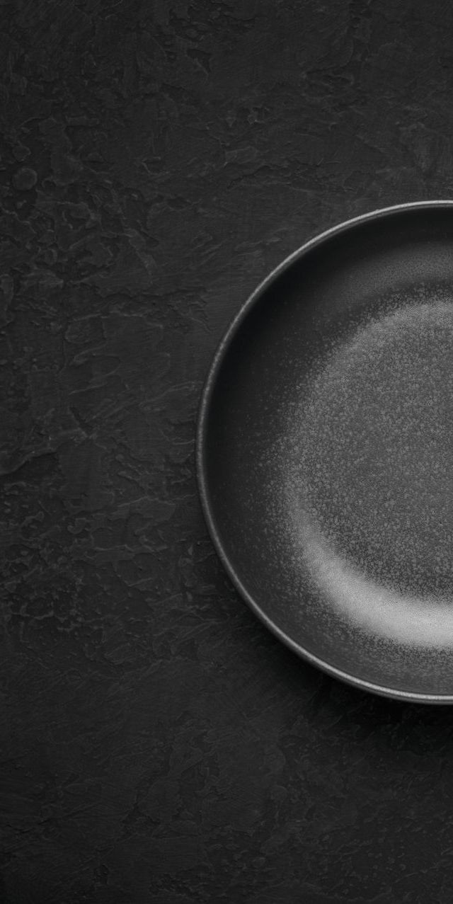 A black plate is sitting on a black table.