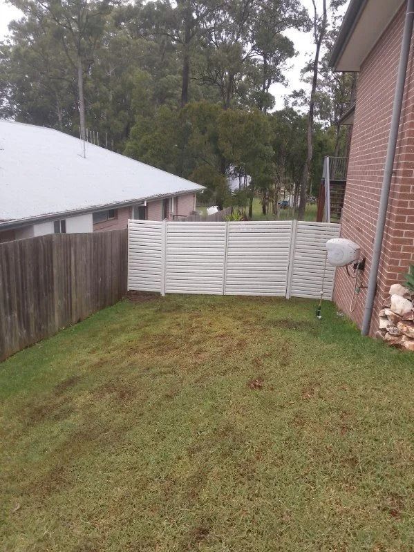 A Residential Backyard With a Grassy Slope, a Wood Fence on the Left — A Betta Fence 'N' Yard In Lake Cathie, NSW