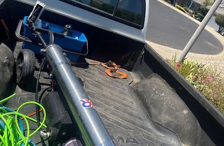 Truck bed with window cleaning equipment and bright green hose.