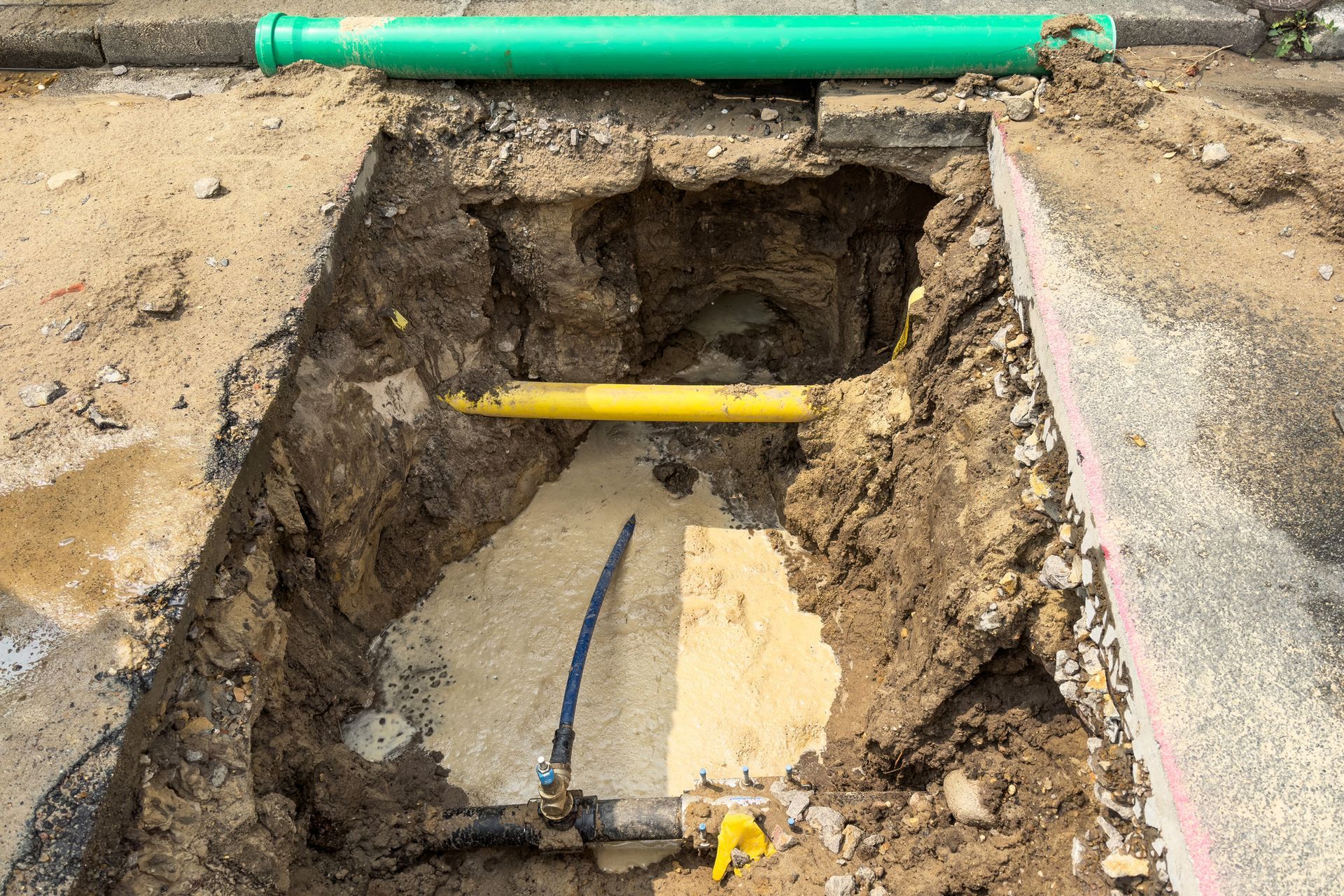 Underground trench exposing damaged pipes during sewer line repair.