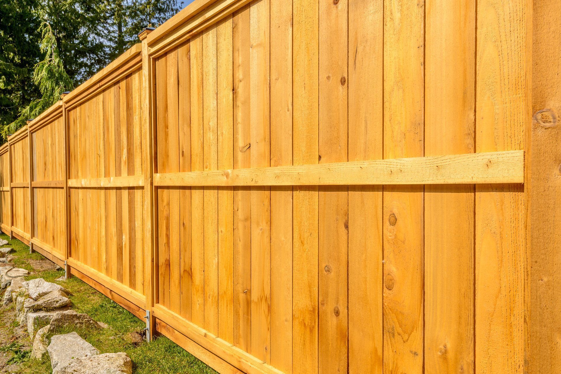 A wooden fence is sitting on top of a lush green field.