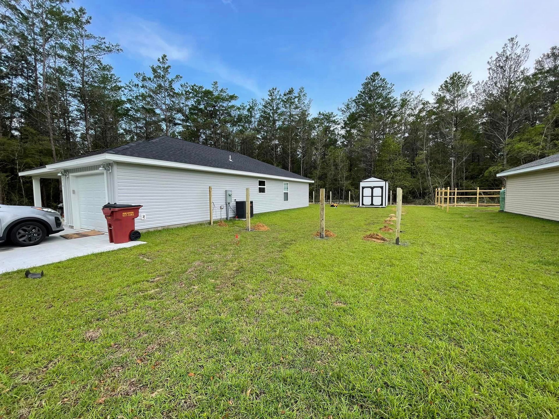 A white house is sitting in the middle of a lush green field.