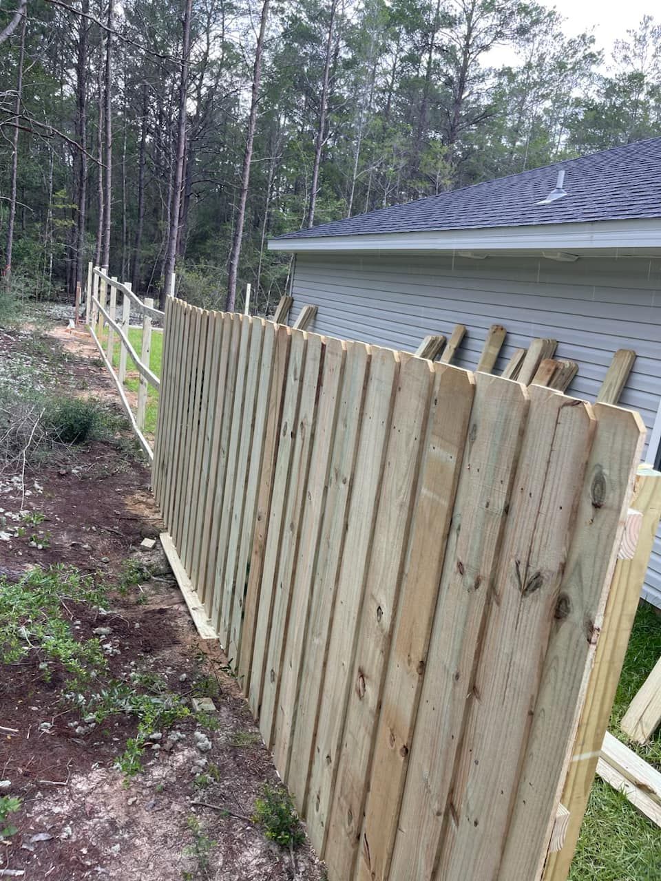 A wooden fence is being built in front of a house.