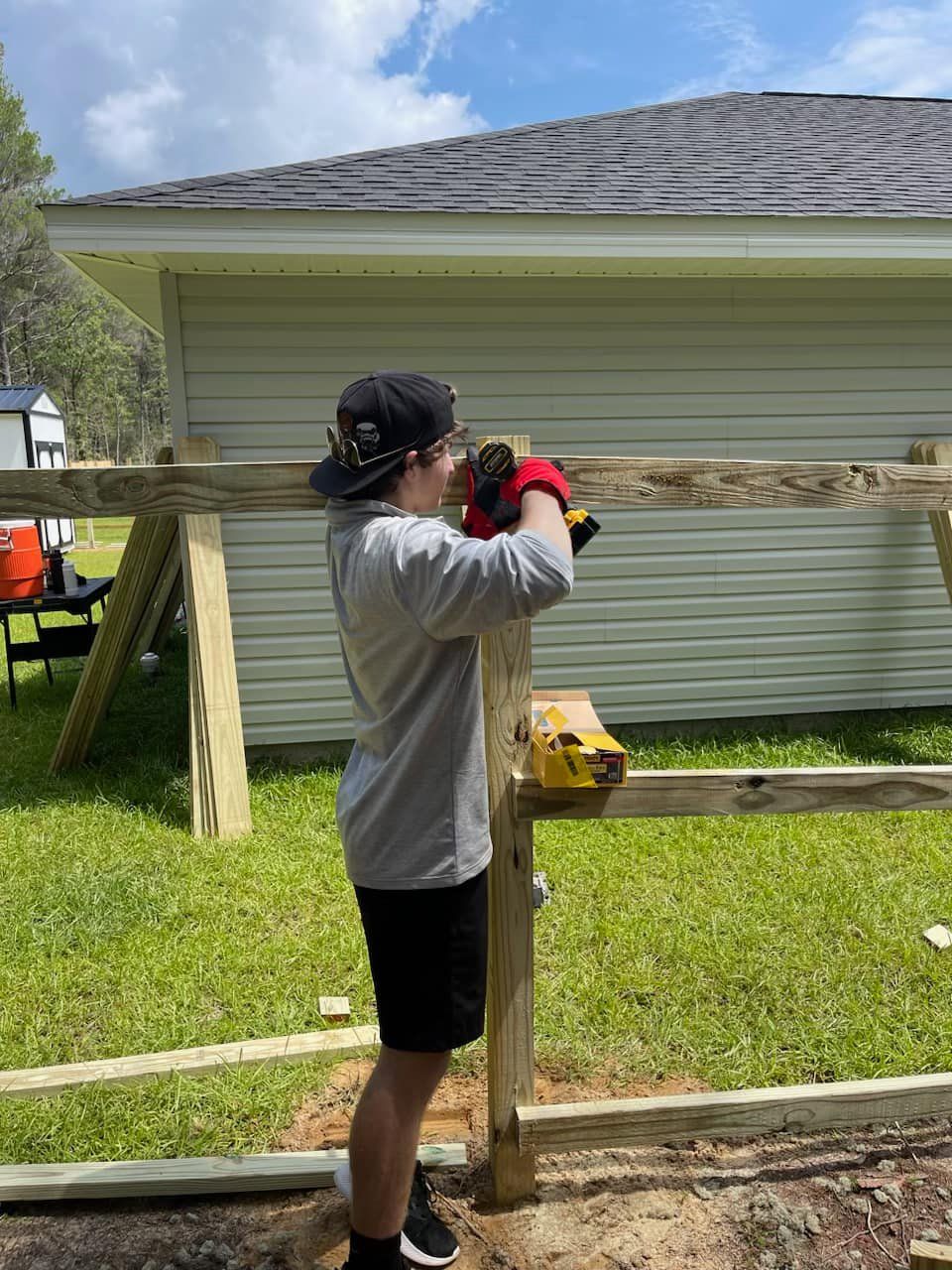 A man is working on a wooden fence in front of a house.