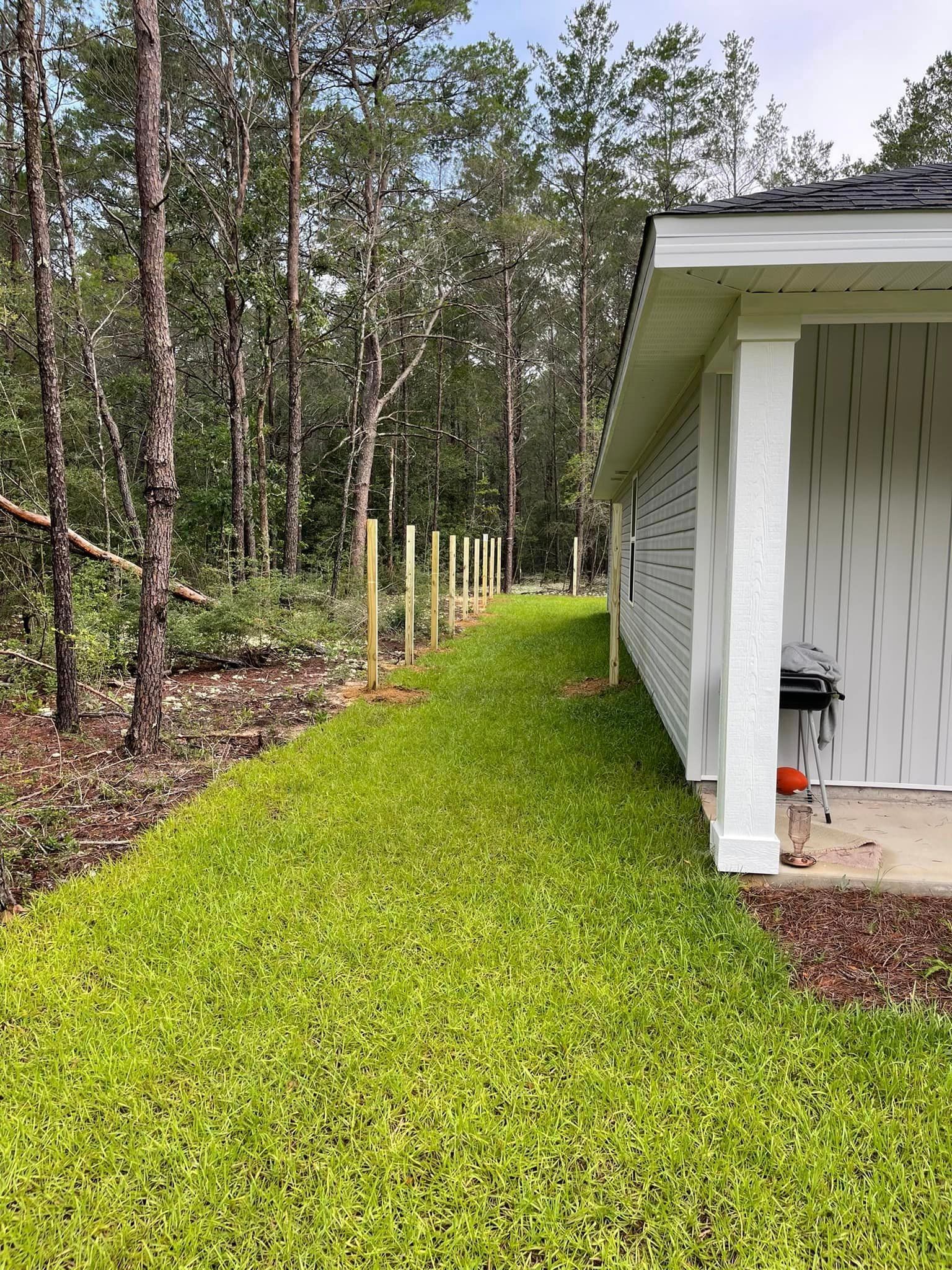 A white house with a wooden fence in front of it surrounded by trees.
