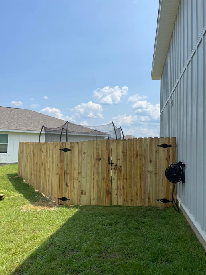 A wooden fence is in the backyard of a house.