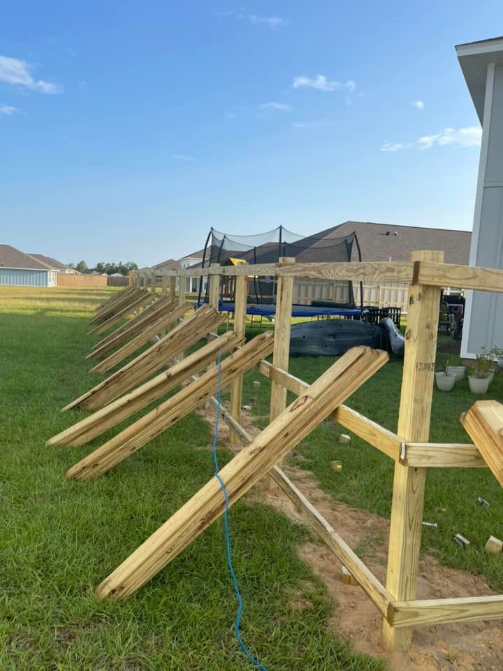 A wooden fence is being built in the backyard of a house.