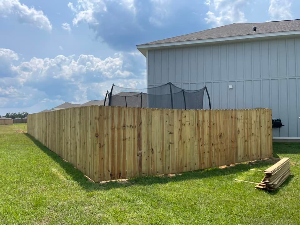 A wooden fence is being built in the backyard of a house.