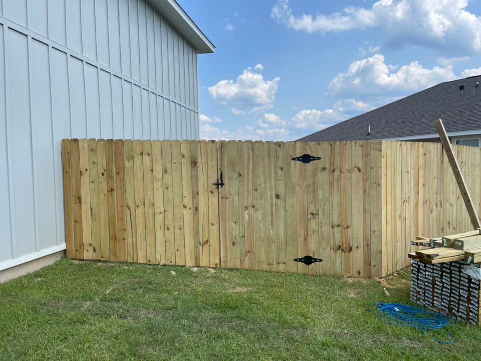 A wooden fence is being built in the backyard of a house.