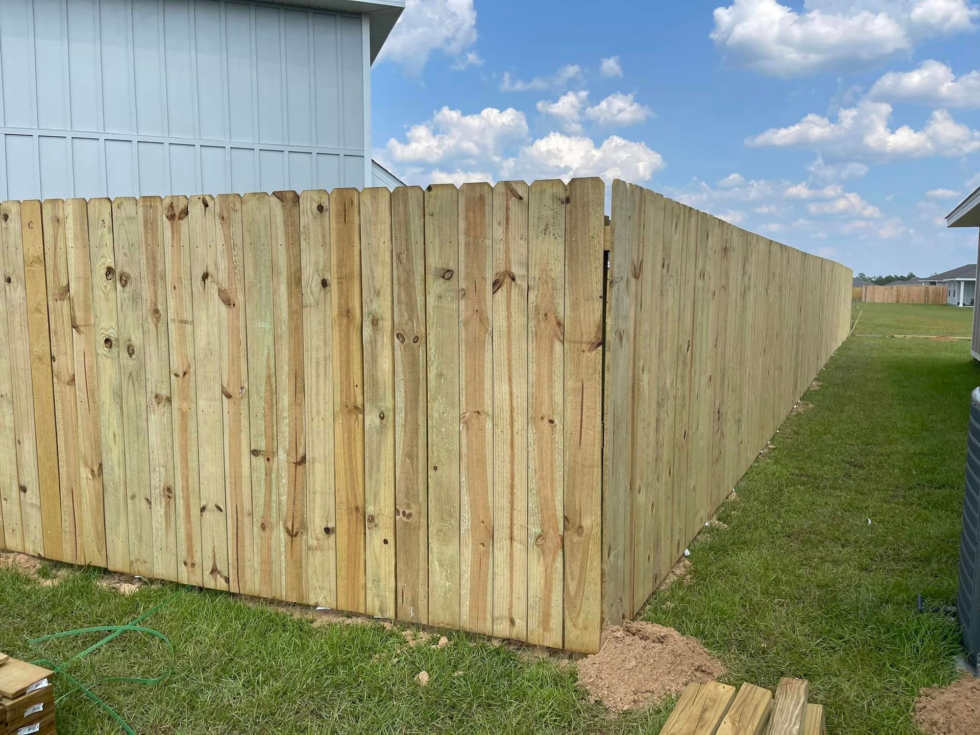 A wooden fence is being built in the backyard of a house.