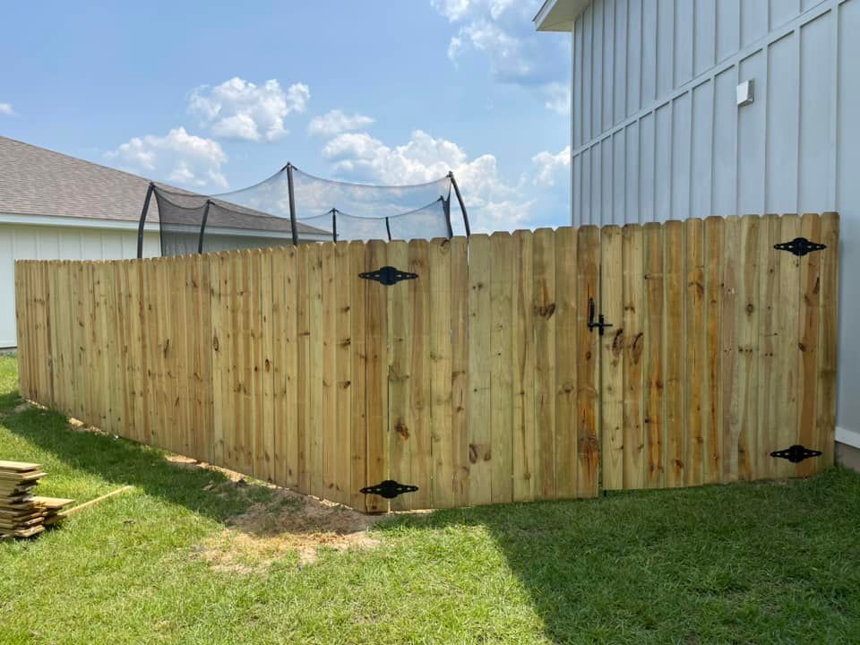 A wooden fence with a gate is in the backyard of a house.