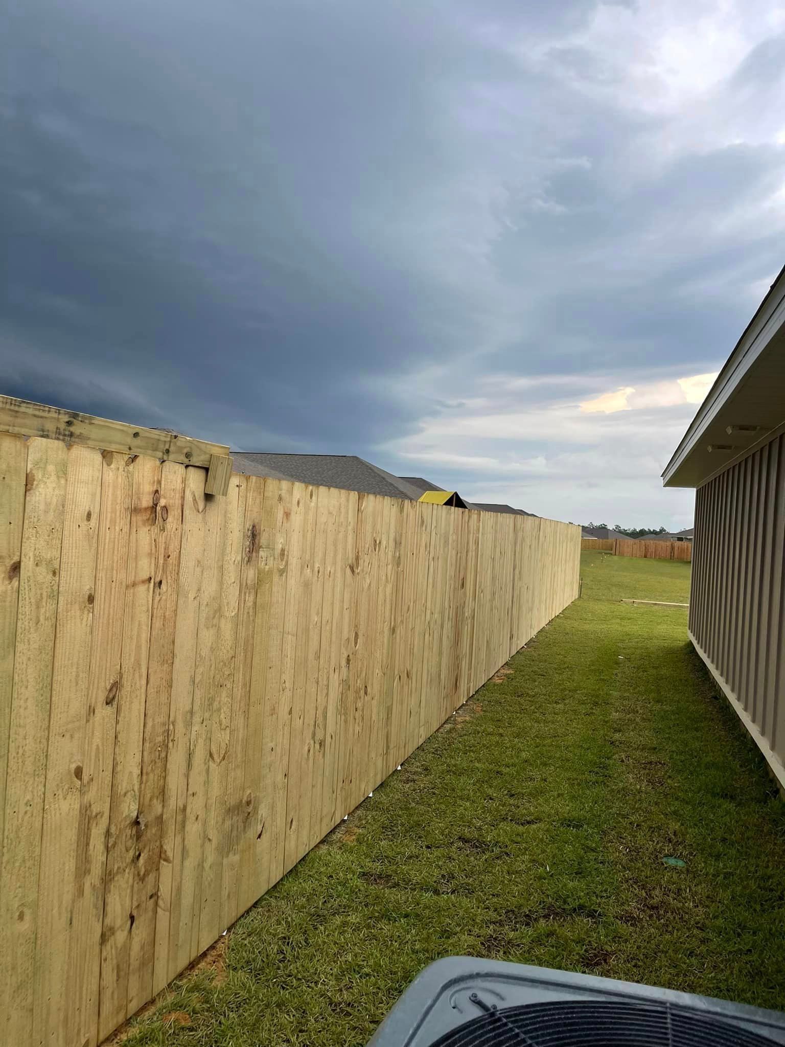 A wooden fence is in the backyard of a house.